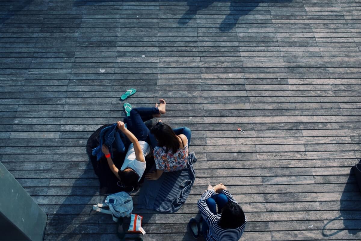 Eine Gruppe junger Menschen, von oben fotografiert, sitzt auf einem Holzsteg
