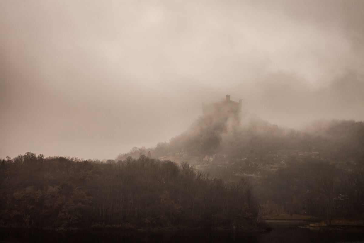 Auf einem nebelverhangenen Berg ist ein Schloss zu sehen