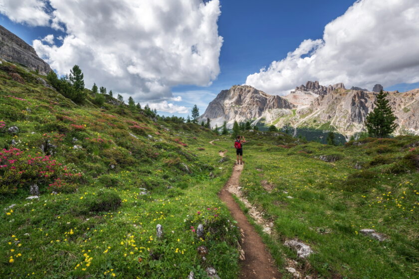 A hiker is standing on a trail in the mountains.