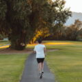 A woman seen from behind is running in a park.