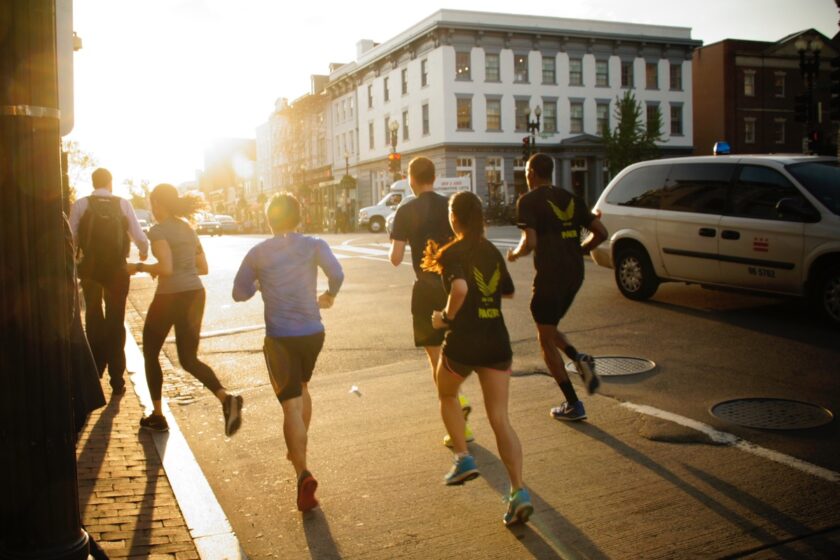 A group of runners in running in the city streets during sunset.